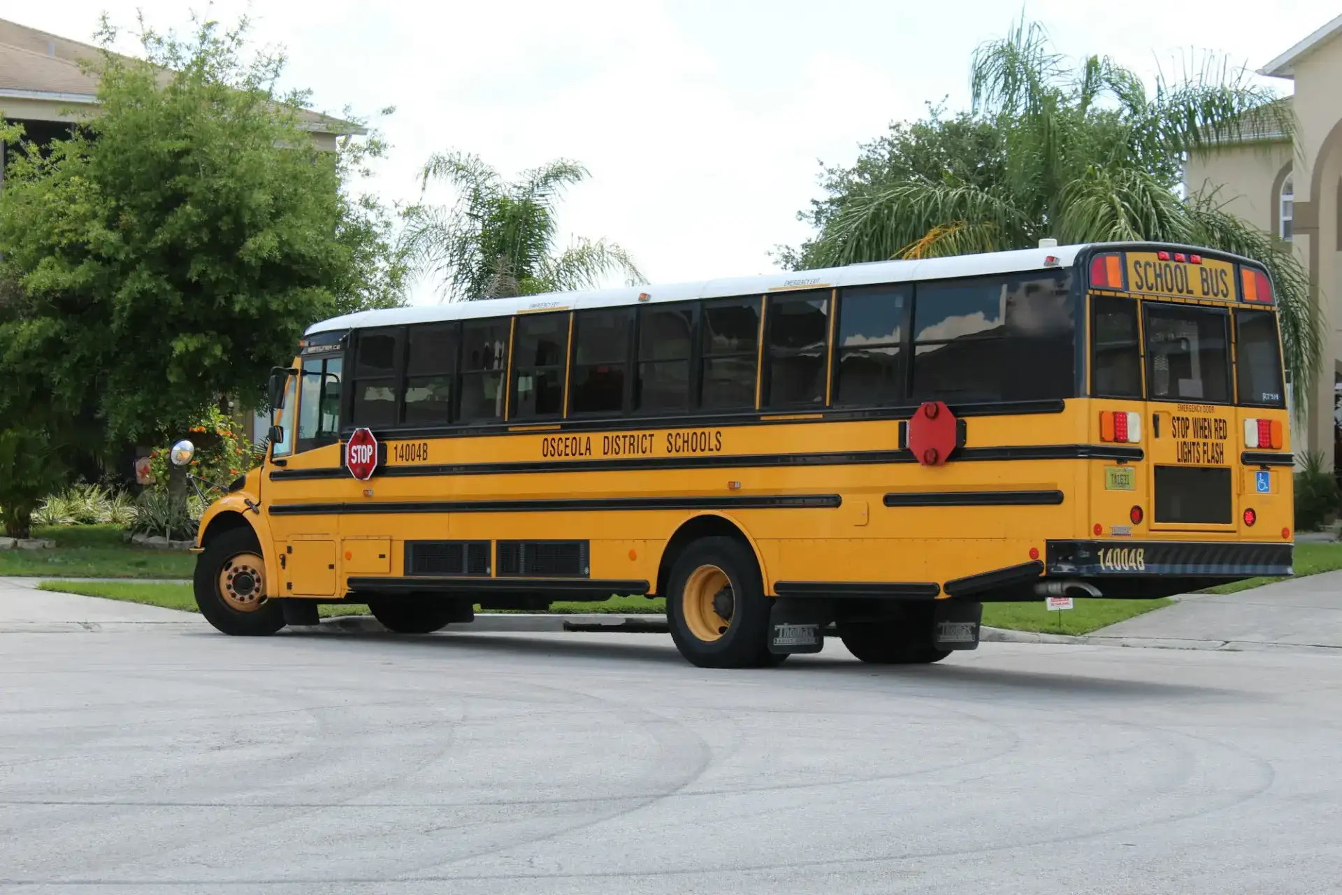 A yellow school bus with its stop arm out seen from the rear corner