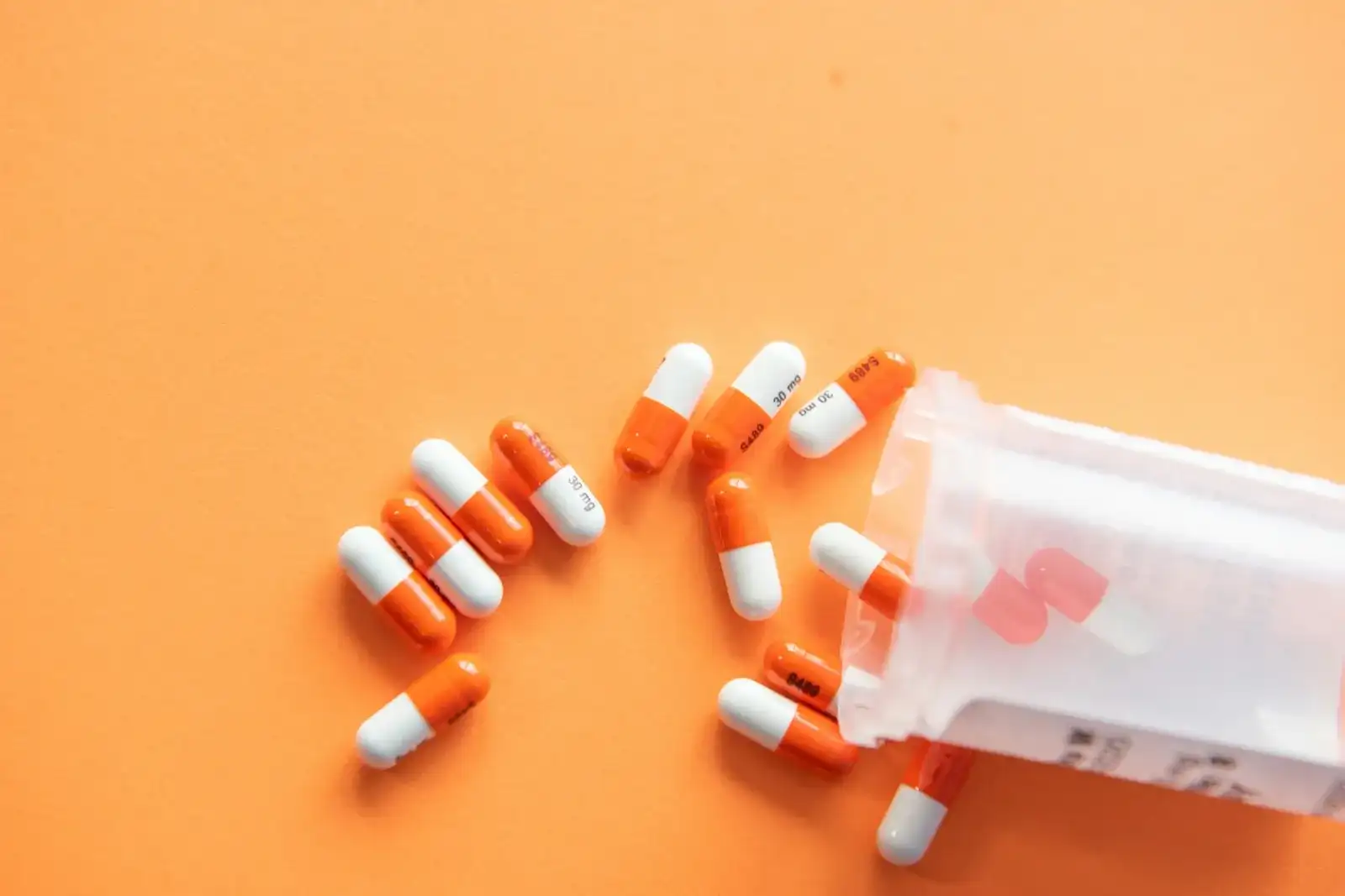 Prescription medication bottles and capsules organized on a white pharmacy dispensing counter