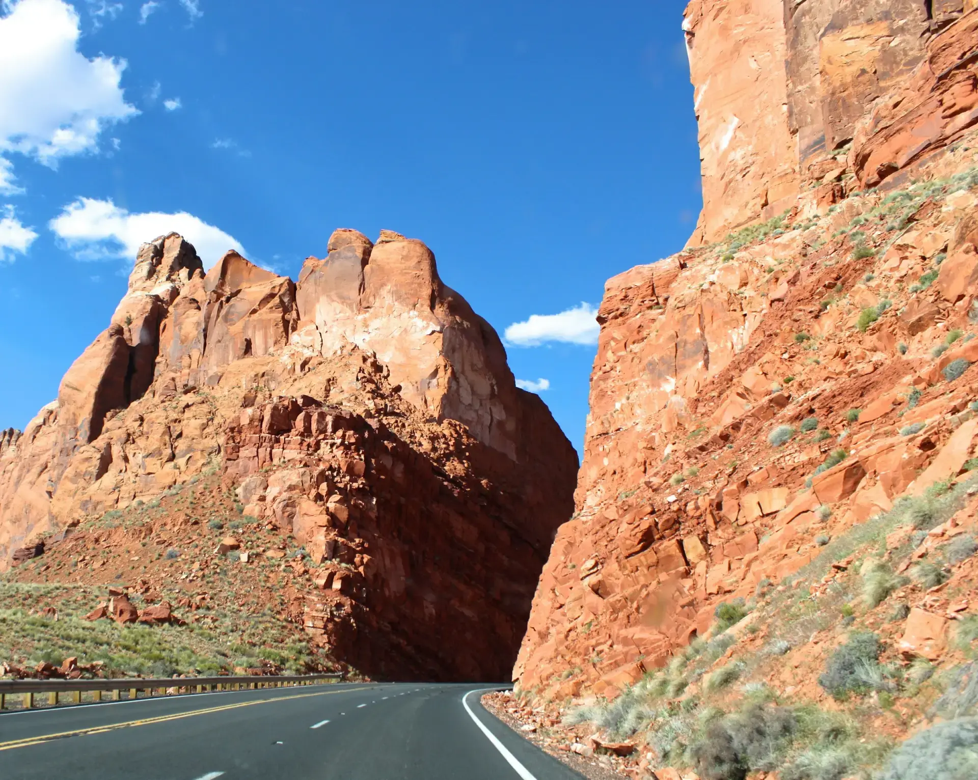 An Arizona highway curving between red rock cliffs under a blue sky