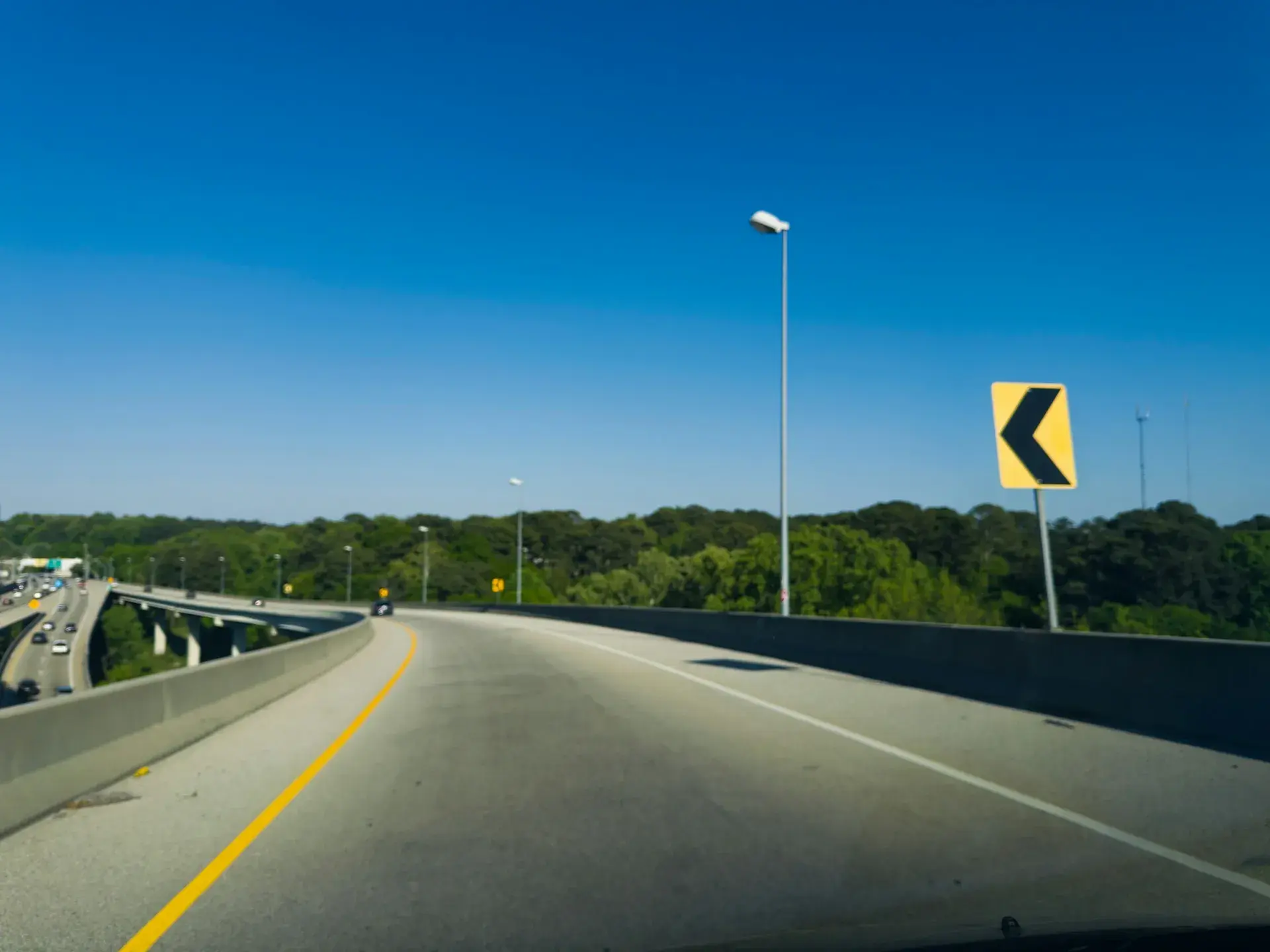 Atlanta highway curving right under a blue sky, with a yellow curve warning sign