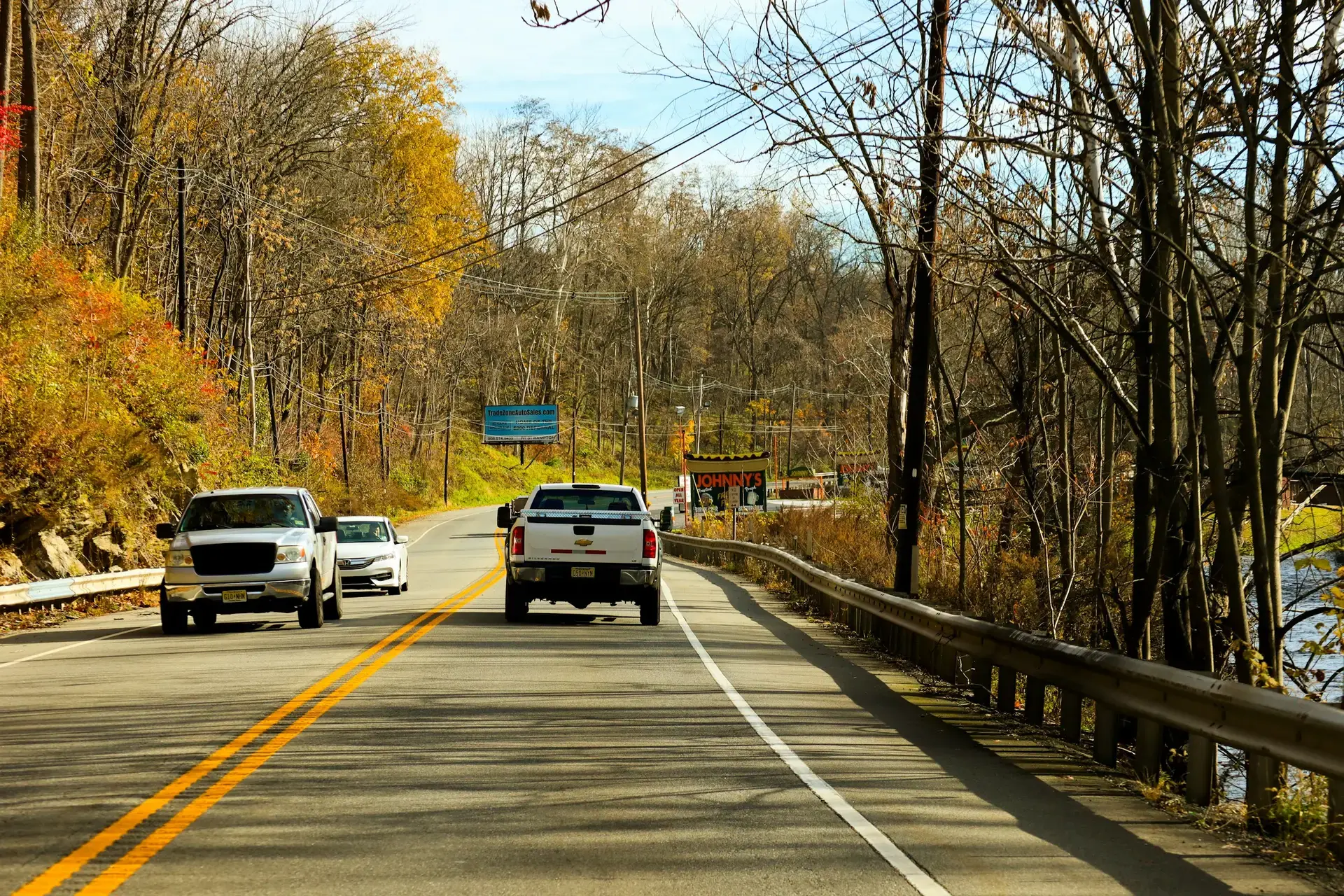 Cars driving on a two-lane New Jersey road lined with autumn trees