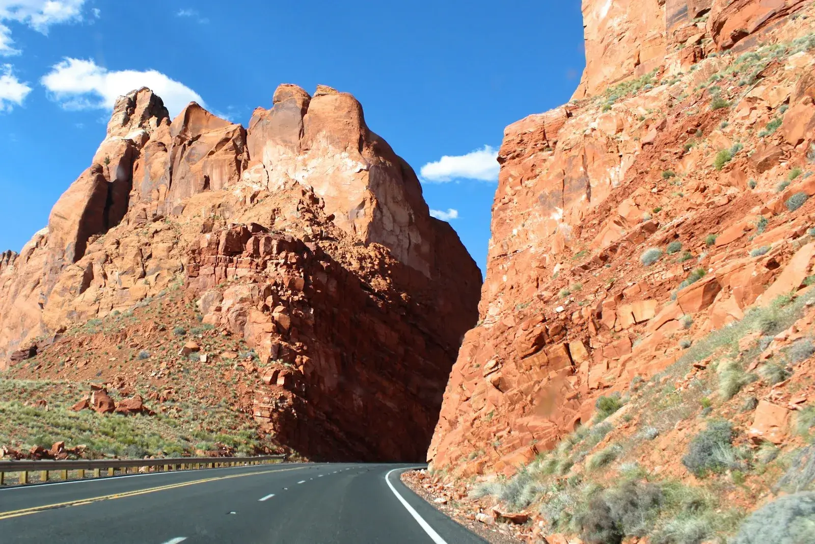 A highway bending between red rock cliffs under a blue sky in Arizona