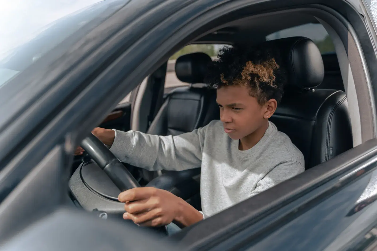 Young driver holding the steering wheel of a parked car